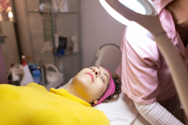 在水疗中心享受面部护理的女性。在健康水疗沙龙做面部手术时放松。女人闭着眼睛等待治疗。小生意。库存图片图片下载