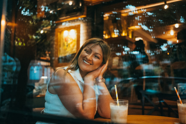 美丽的年轻女子在下雨天在酒吧喝意大利浓缩咖啡-照片从外面的玻璃反射效果图片下载