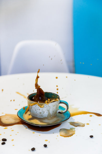 这张美丽的照片是在咖啡店的白色桌子上，杯子里的卡布奇诺咖啡洒在绿松石色的茶托上图片下载