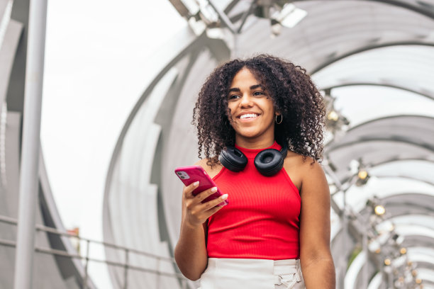 一个留着非洲发型的女孩在城市里玩智能手机的照片图片下载