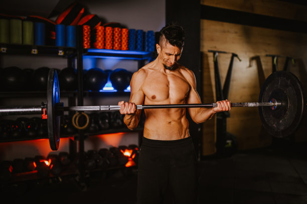 一个光着膀子的男人在健身房举重锻炼的照片图片下载