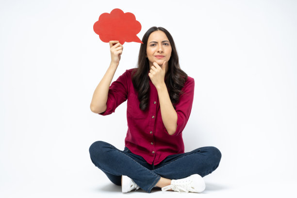 开朗可爱的女人穿着时髦的衣服，坐在地板空空间孤立的白色背景股票照片图片下载