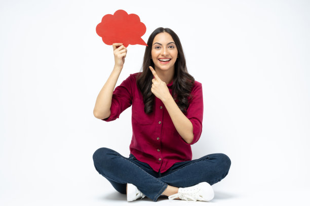 开朗可爱的女人穿着时髦的衣服，坐在地板空空间孤立的白色背景股票照片图片下载