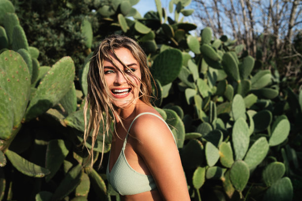 开朗的年轻女子在充满活力的仙人掌周围摆姿势图片下载