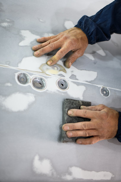 在车库里重新喷漆前，穿着西装的工人从汽车部件上取下抛光剂的无脸照片图片下载