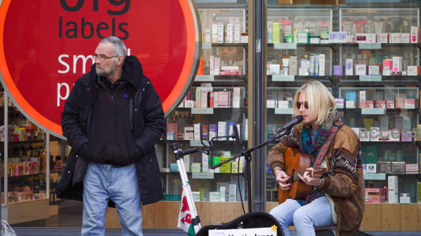 一个年轻人拿着吉他在商店外面卖艺图片下载