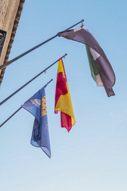 阳光明媚的日子里，西班牙埃斯特雷马杜拉自治区和纳瓦尔莫勒尔德拉马塔市的旗帜在蓝天下飘扬图片下载