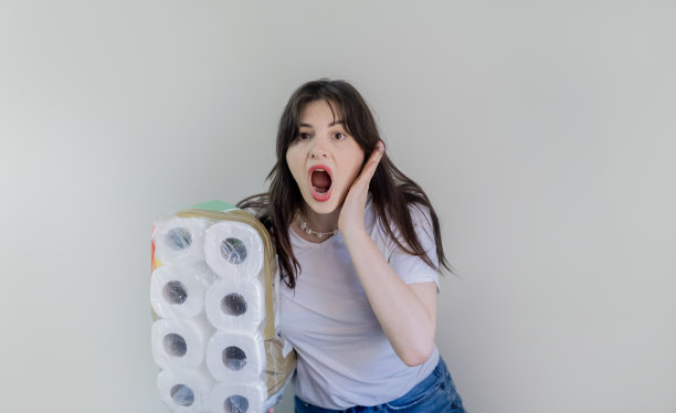 买了一大包卫生纸，女人拿着灰色背景的卫生纸，上门为家庭用品送货。图片下载