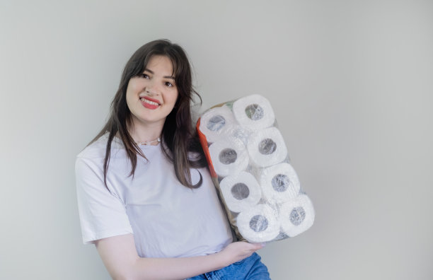 买了一大包卫生纸，女人拿着灰色背景的卫生纸，上门为家庭用品送货。图片下载