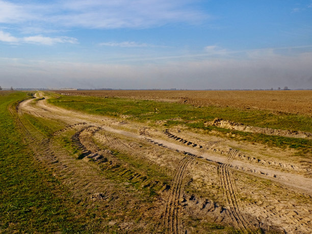 这张照片拍摄了一个宁静的乡村环境，以田野和蜿蜒的小路为特色。图片下载