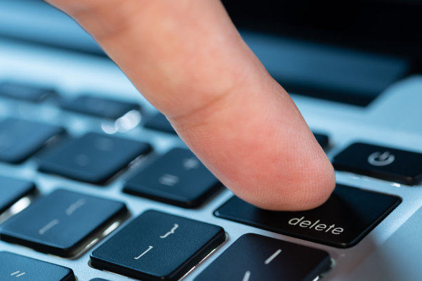 电脑用户的手指，他按下了电脑键盘上的删除键。图片下载