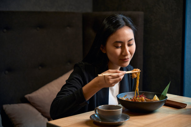 饥饿的亚洲妇女在舒适的餐厅享用美味的海鲜拉面图片下载