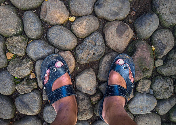穿着黑色凉鞋的两只脚在岩石上的照片图片下载