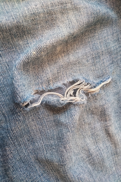 特写的破洞牛仔裤与堆，磨损和撕裂的衣服，垂直照片图片下载