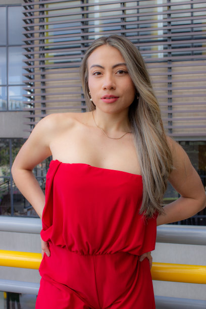 美丽的年轻女子穿着红色连衣裙，在一座桥上摆姿势，背景是一座建筑图片下载