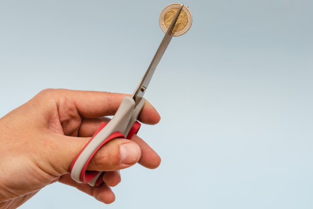 剪刀剪硬币(欧元)在蓝色背景图片下载