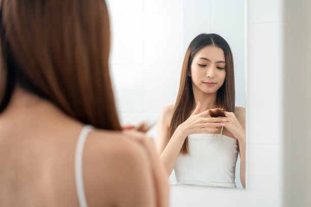 自信的女人照镜子，梳理头发，欣赏自己的身材。年轻的亚洲美女谁照顾自己很好。检查面部皮肤图片下载