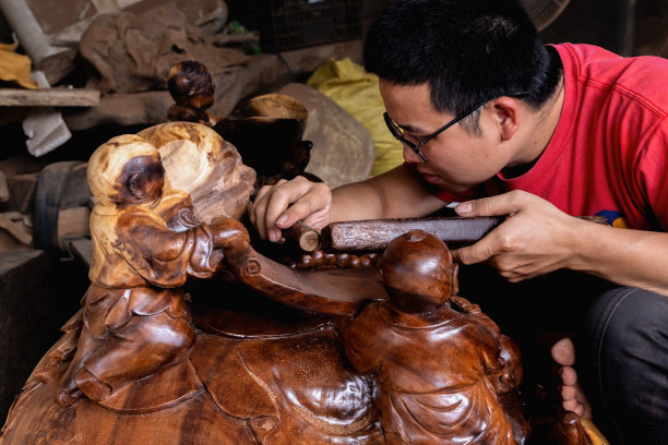 一名戴眼镜的亚洲男子用手雕刻木雕的侧面照片。图片下载