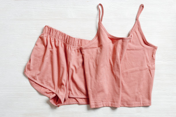 白色木制背景上的粉色睡衣。夏夜西装睡觉，折叠的衣服，背心和短裤俯视图照片。女士睡衣最小平躺式，舒适睡眠图片下载