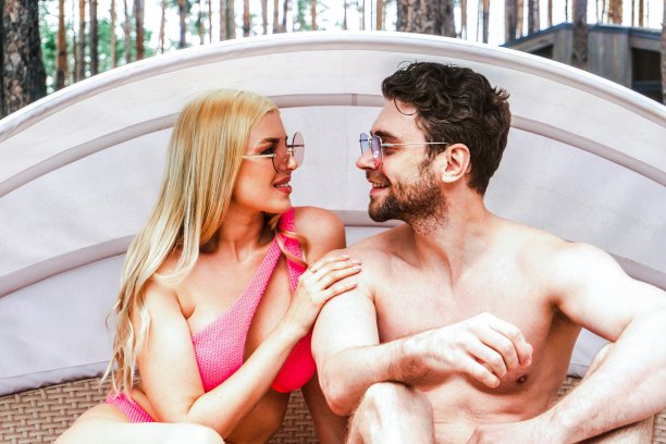 幸福的年轻夫妇戴着墨镜，在泳池边度过周末，看着对方。暑假，恋爱，生活方式概念图片下载