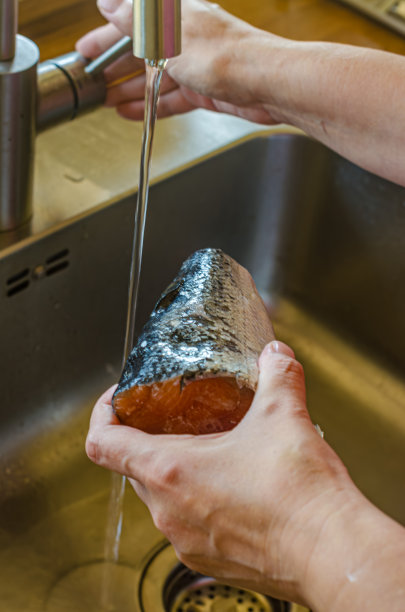 妇女正在用手清洗鲑鱼的一部分图片下载