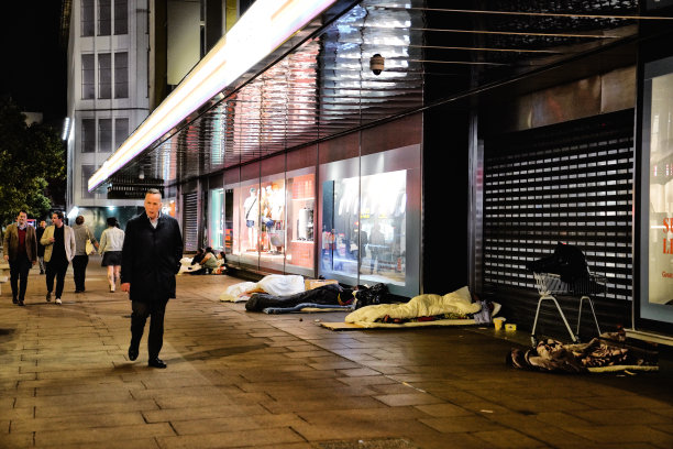 在牛津街的标志性商店(John Lewis & Partners商店)外使用羽绒被和睡袋的无家可归者夜景:伦敦无家可归者图片下载
