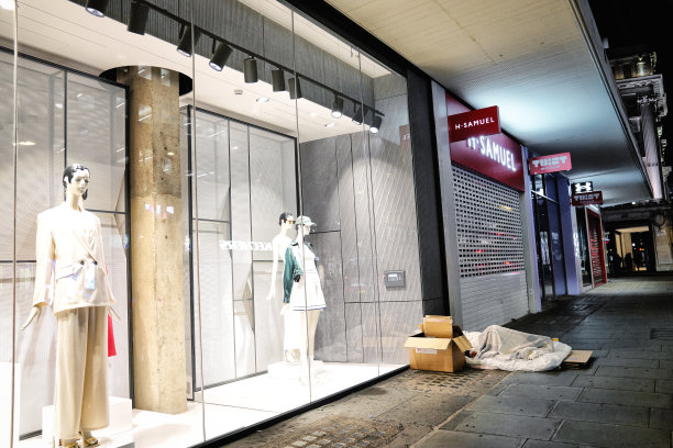 在牛津街的标志性商店(John Lewis & Partners商店)外使用羽绒被和睡袋的无家可归者夜景:伦敦无家可归者图片下载