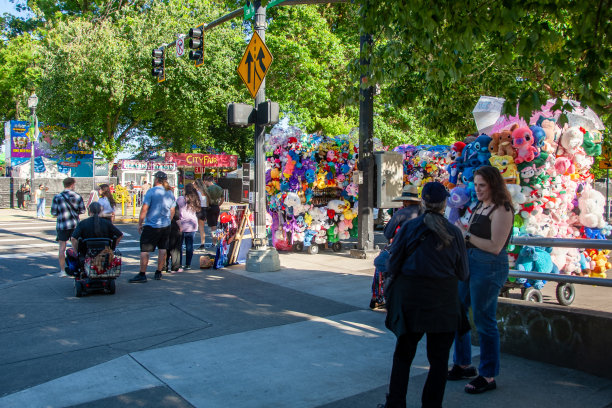 在SW Naito Parkway和Harvey Milk的十字路口，街头小贩出售彩色毛绒玩具，附近站着一群人。(HDR照片)图片下载
