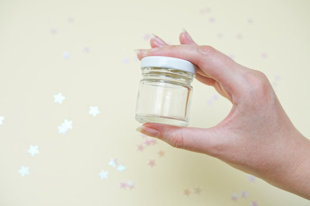 女人手里拿着装蜂蜜或液体、药片、药片的小玻璃瓶。图片下载