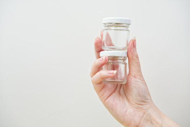 女人手里拿着装蜂蜜或液体、药片、药片的小玻璃瓶。图片下载