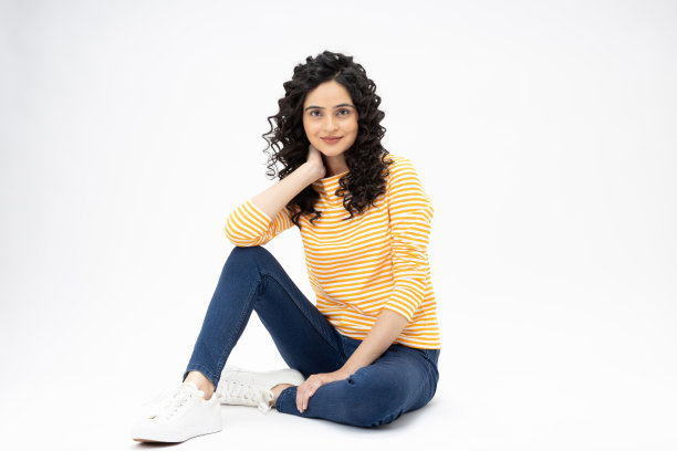 开朗可爱的女人穿着时髦的衣服，坐在地板空空间孤立的白色背景股票照片图片下载