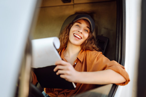 美丽的年轻女子的肖像专业卡车司机坐在一辆大卡车。图片下载