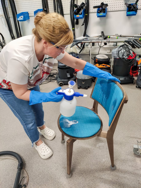 一个年轻的女人清洗椅子，把化学清洁剂涂在椅子的内饰上。图片下载