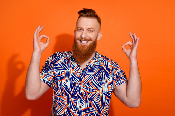 照片自信开朗的家伙穿着印花衬衫显示两个ok的标志孤立的橙色背景图片下载