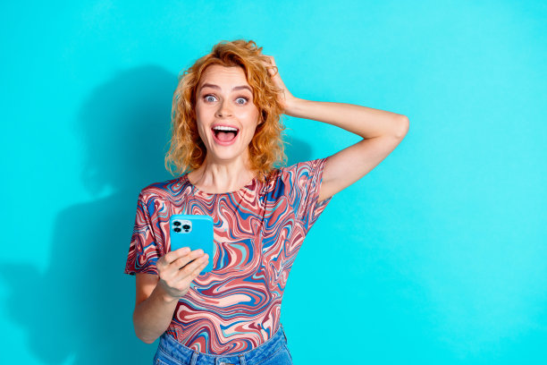 照片中的美女智能手机空着空间，穿着t恤孤立在蓝绿色的背景上图片下载