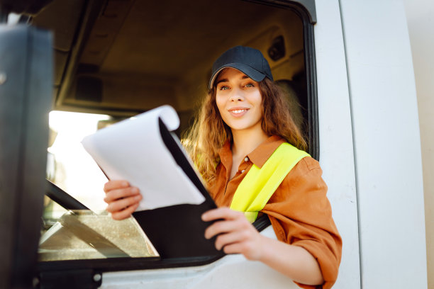 美丽的年轻女子的肖像专业卡车司机坐在一辆大卡车。图片下载