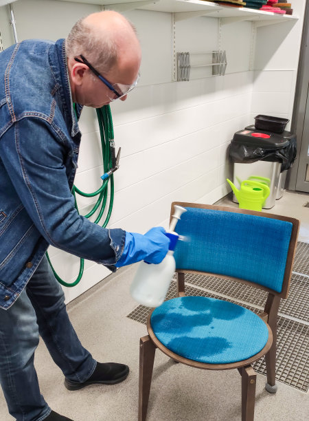 一个男人正在清洗椅子，把化学清洁剂涂在椅子的内饰上。图片下载