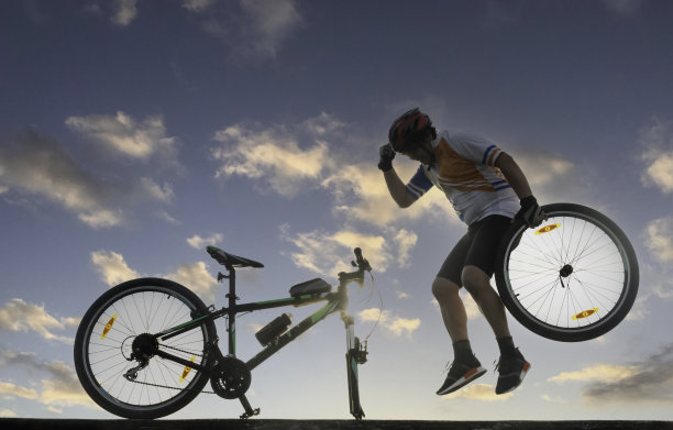 一个骑自行车的人在天空的背景下修理自行车图片下载