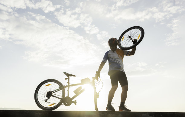 一个骑自行车的人在天空的背景下修理自行车图片下载