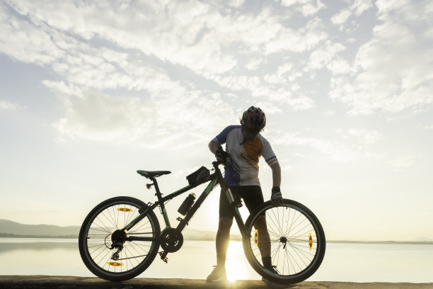一个骑自行车的人在天空的背景下修理自行车图片下载