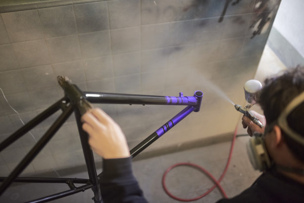 一名男子在他的车间里喷涂自行车车架，并涂上一层保护性的透明涂层图片下载