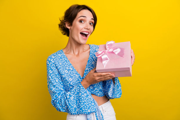 照片无忧无虑的兴奋的女士穿着花印花顶部上升粉红色礼盒孤立的黄色背景图片下载