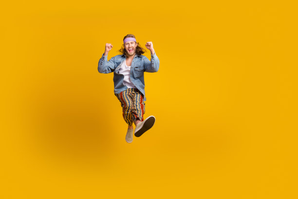 全尺寸照片的酷年轻人坐在行李箱空空间穿牛仔衬衫孤立的黄色背景图片下载