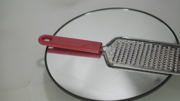 这个奶酪刨丝器或其他刨丝器是由不锈钢制成的，带有红色塑料手柄图片下载