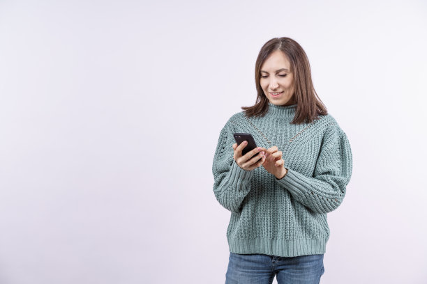 一个女人看着她的手机，面带微笑图片下载