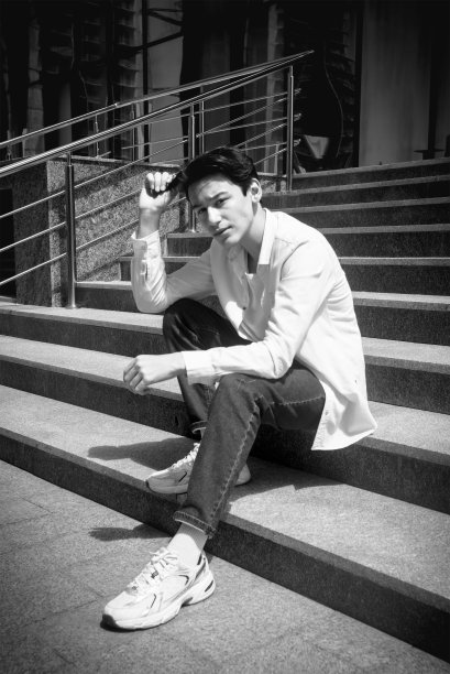 年轻人，十几岁的模特坐在城市的台阶上。休闲、时尚。BW颗粒照片图片下载