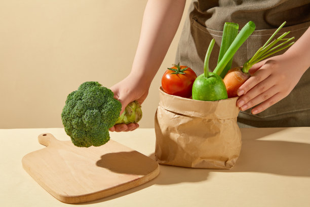 厨房背景照片，从正面角度拍摄，厨师把一个绿色的卷心菜放在一个木制砧板上，放在桌子旁边的一袋蔬菜。广告留白图片下载