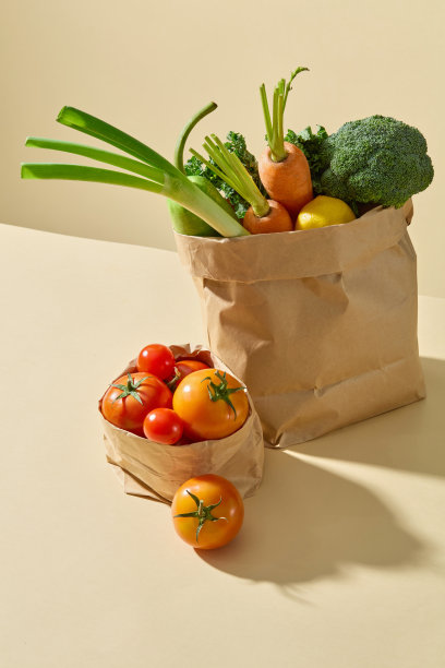 黄色的台面上有两个纸袋放在一起，都装有新鲜的蔬菜原料。广告照片为烹饪，饮食或素食图片下载