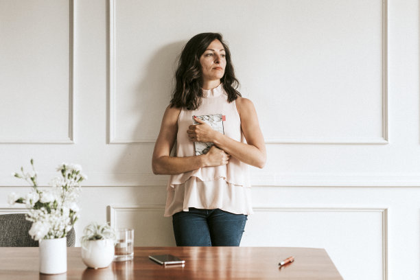 女商人拿着一本大理石质地的书靠墙站着图片下载