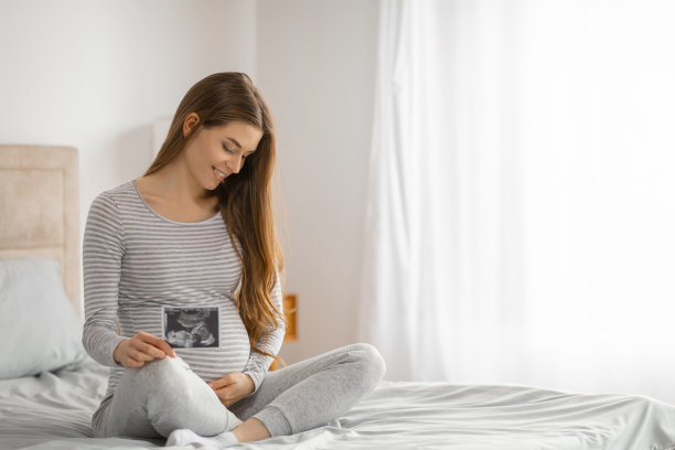 孕妇在床上拿着超声波照片图片下载